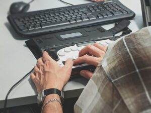Personne utilisant un afficheur braille relié à un ordinateur