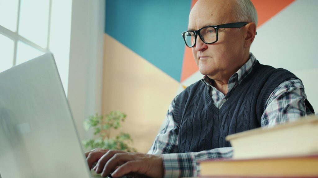 Homme âgé consultant un site internet sur son ordinateur portable
